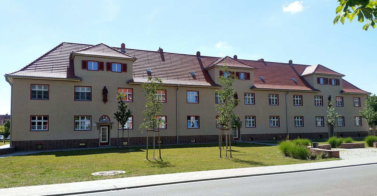 Außenansicht Mehrfamilienhaus mit begrünten Vorbereich . Sanierung Eisenbahnersiedlung, Elstal/ Wustermark